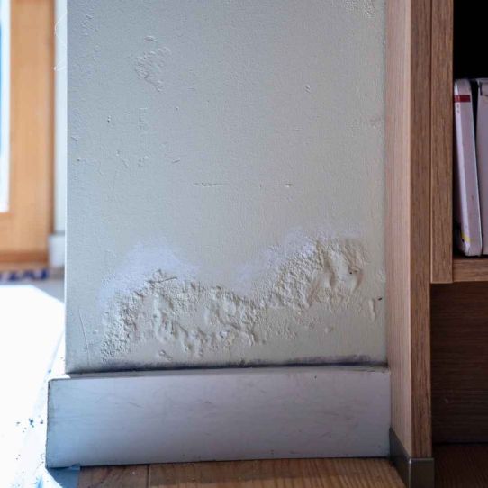Vochtplekken en afbladderende verf op de binnenmuur 