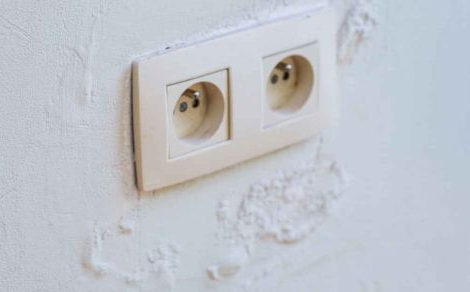 Blaasjes op de muur door optrekkend vocht rond een stopcontact