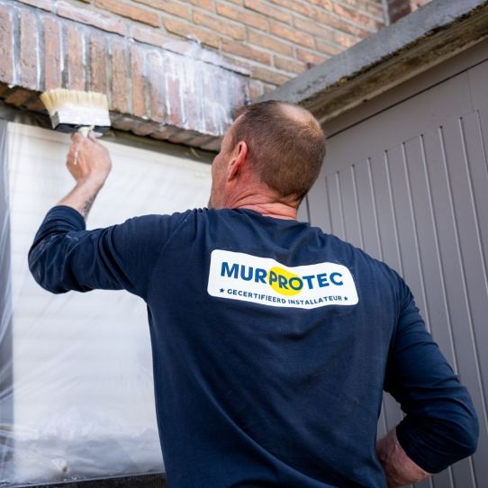 Een vochtspecialist van Murprotec impregneert de gevel 