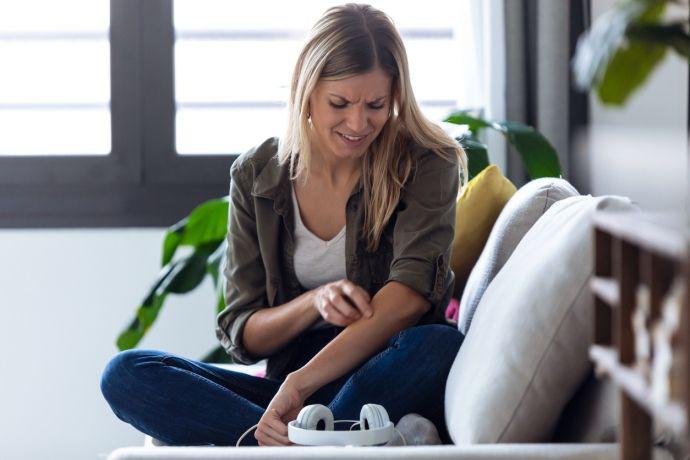 Jonge vrouw heeft jeuk aan haar arm 