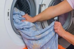 Iemand haalt beddengoed uit de wasmachine